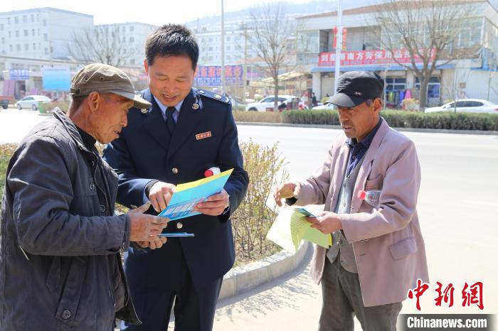 图为韩晓东(中)走街串巷为民众讲解相关知识。　平凉工业园区税务局供图