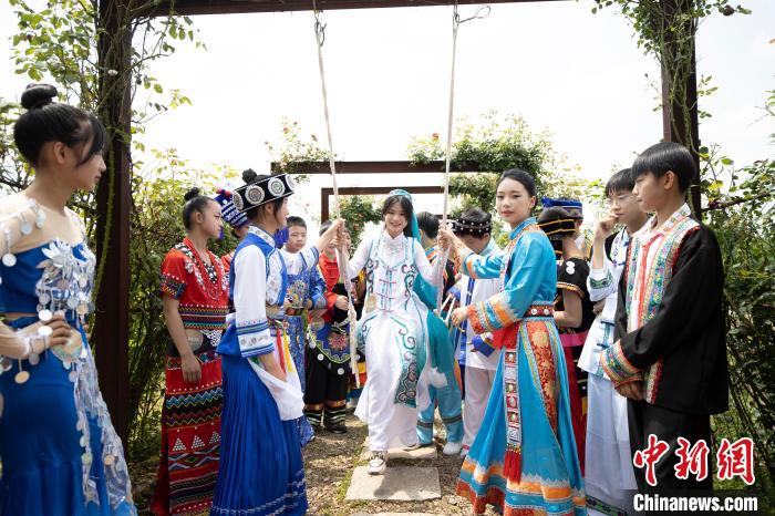 身着各民族传统服饰的学生在玫瑰长廊荡秋千 施紫楠 摄 摄