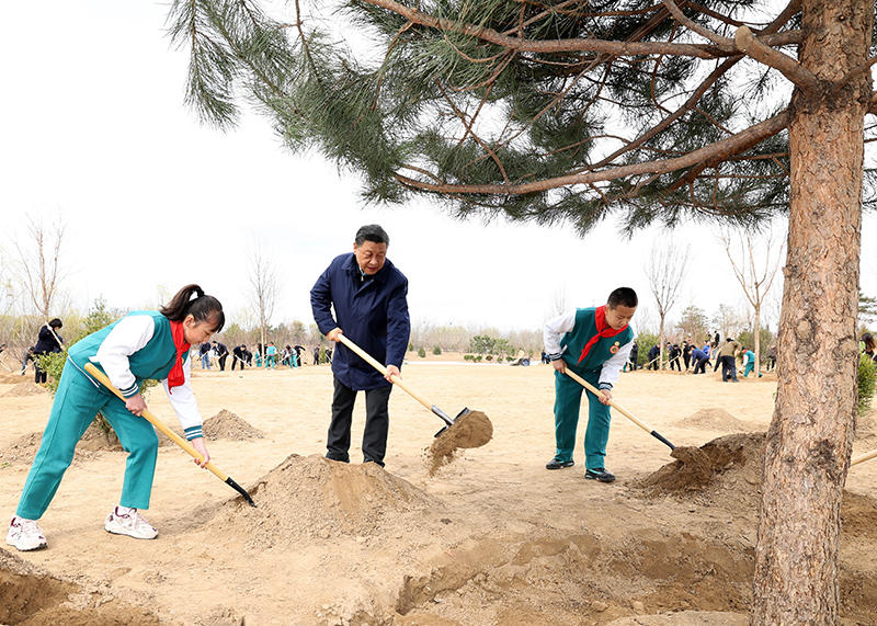 　2022年3月30日，习近平等党和国家领导人来到北京市大兴区黄村镇参加首都义务植树活动。这是习近平同大家一起植树。