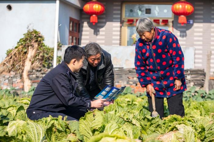 　江苏省泰州市海陵区苏陈派出所民警在苏陈社区田间地头向农户进行普法宣传(2021年12月4日摄)。新华社发(汤德宏 摄)