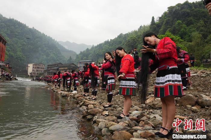 4月22日，在广西龙胜各族自治县龙脊镇黄洛瑶寨，当地瑶族民众在河边开展长发梳妆表演。　韦吉阳 摄