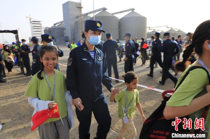 当地时间4月26日，海军军舰赴苏丹紧急撤离我在苏丹人员。图为海军官兵手牵着儿童通过安检。　丁家兴 摄