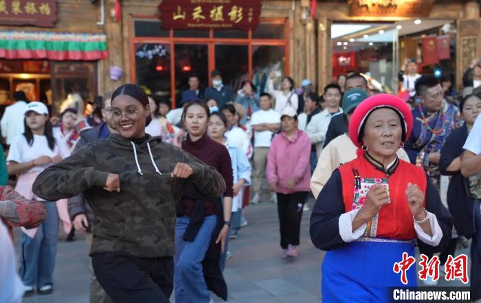 图为“Z世代”海内外青年在独克宗古城与当地居民及游客跳舞。　何显津 摄