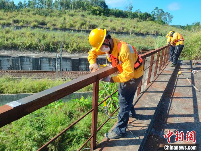 图为高温下南宁工务段桥梁工全副武装对铁路桥梁人行道栏杆打磨除锈。　冯博 摄