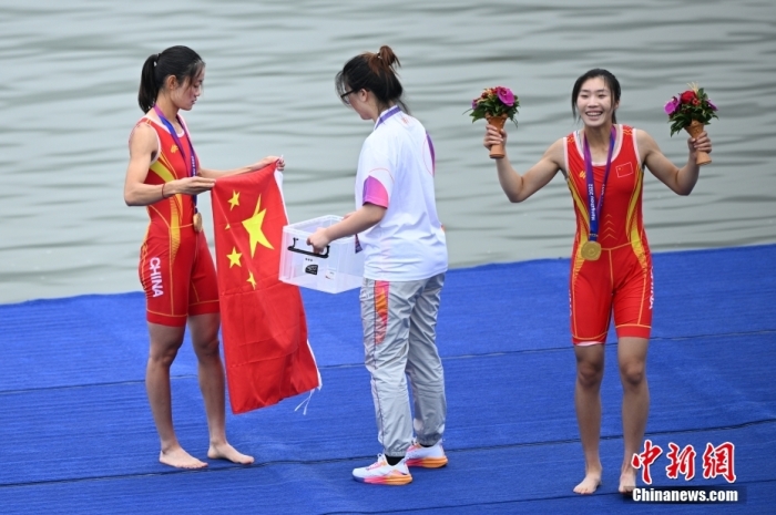 9月24日，杭州第19届亚运会赛艇女子轻量级双人双桨决赛在浙江杭州举行，中国组合邹佳琪、邱秀萍以7分06秒78的成绩夺冠。这是本届亚运会的首枚金牌。图为邱秀萍(左)在颁奖仪式后整理国旗。<a target='_blank' href='/'>中新社</a>记者 王刚 摄