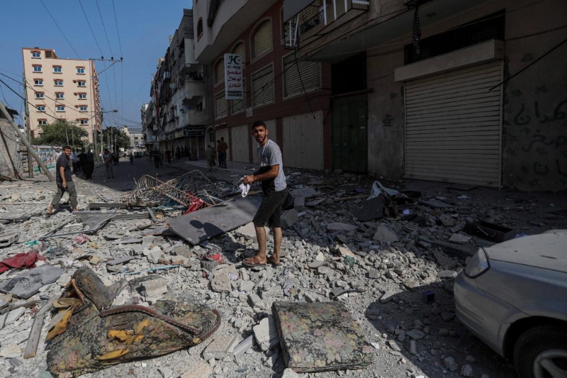 11月2日，人们走过遭以军空袭后的加沙城房屋废墟。（图源：新华社）
