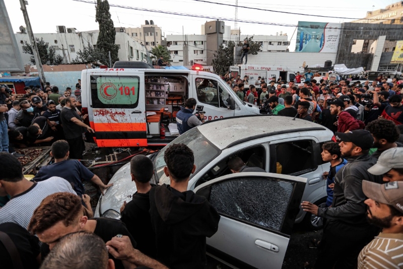 11月3日，在加沙城希法医院门口，人们查看被袭击的车辆。（图源：新华社）