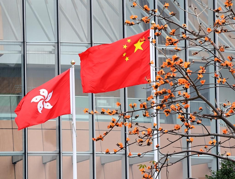这是在香港特区立法会综合大楼外拍摄的中华人民共和国国旗、香港特区区旗。（图源：新华社）