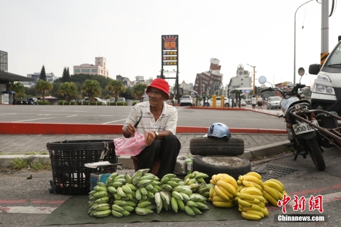 资料图：台湾花莲市区博爱路早市，商贩在街头摆摊售卖水果，不远处是因震倾斜严重的天王星大楼。 中新社记者 杨程晨 摄.jpg